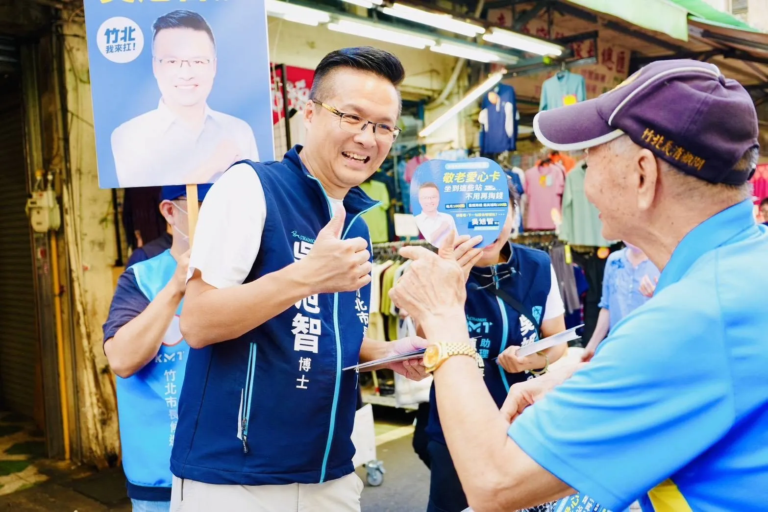 吳旭智與長輩一同查看文宣內容，說明敬老愛心卡及鐵道出遊資訊。（圖/吳旭智競辦提供）