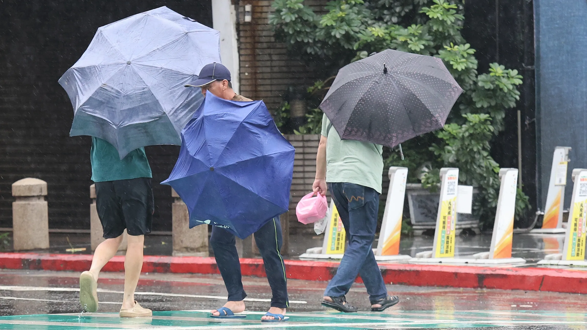 薔琵颱風風雨預計25日（周日）才明顯趨緩，外出民眾撐傘雨中行。（圖／柯承惠攝）