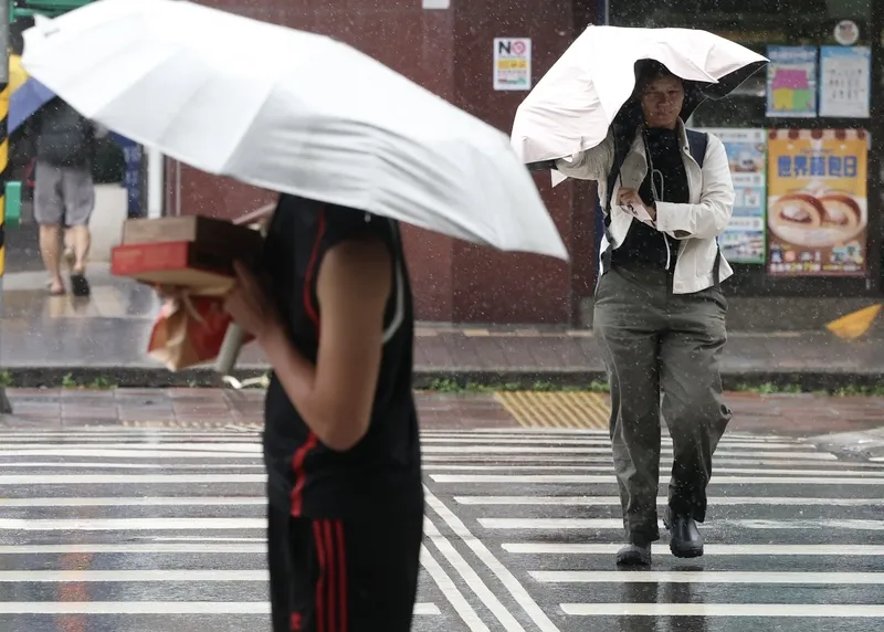 薔琵颱風影響持續到24日，台北市區23日出現明顯風雨，民眾在強勁陣風中撐傘前行。（圖／中央社記者趙世勳攝）