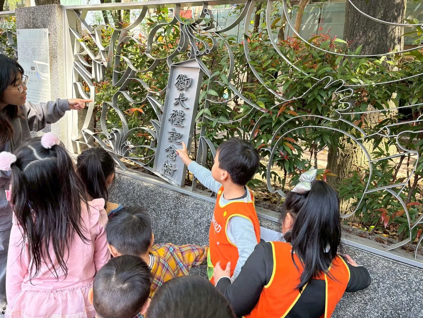 東園國小幼兒園孩子化身「小小鐵花窗導覽員」，在教師陪伴下，指認作品中的「御大禮記念樹」文字，透過觀察、解說與同儕互動，認識鐵花窗承載的校園歷史。（圖/東園國小提供）