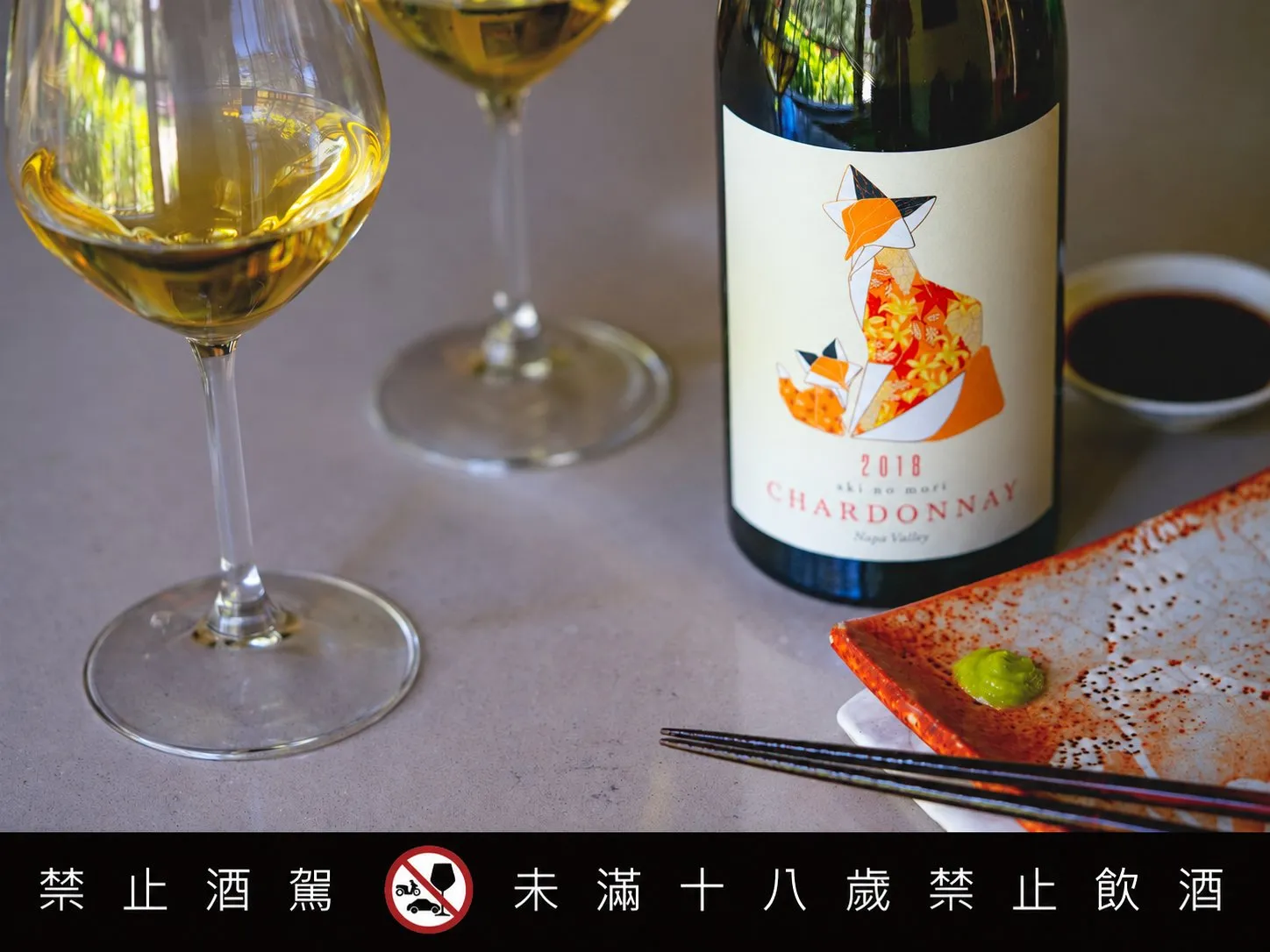 瓶身標有「CHARDONNAY」的白葡萄酒搭配和風餐盤與筷子，與兩只斟上白酒的酒杯一同擺上餐桌