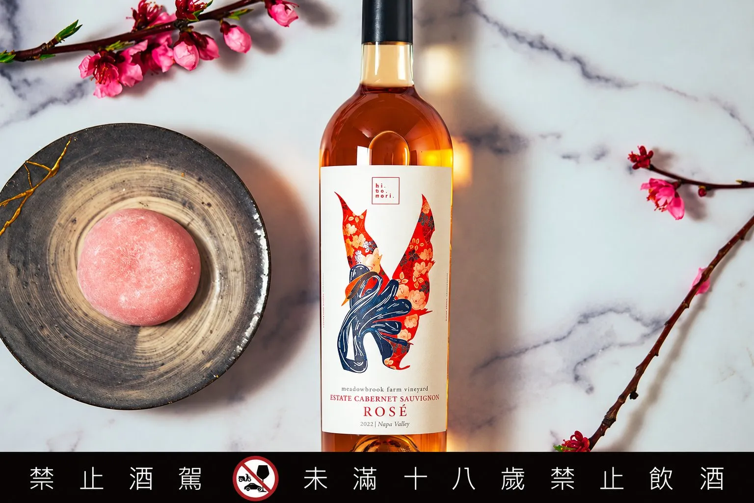 火鳳凰粉紅酒與盤中粉色點心、花枝一同擺放在大理石桌面上