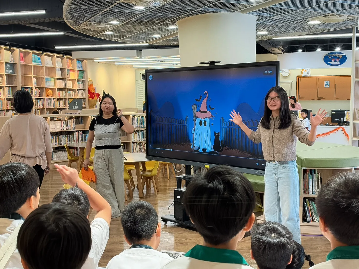 仁愛國小圖書館舉辦萬聖節英文說故事活動，現場搭配圖像與肢體動作引導，學生舉手參與互動，在故事情境中練習聆聽與表達。（圖／臺北市仁愛國小提供）