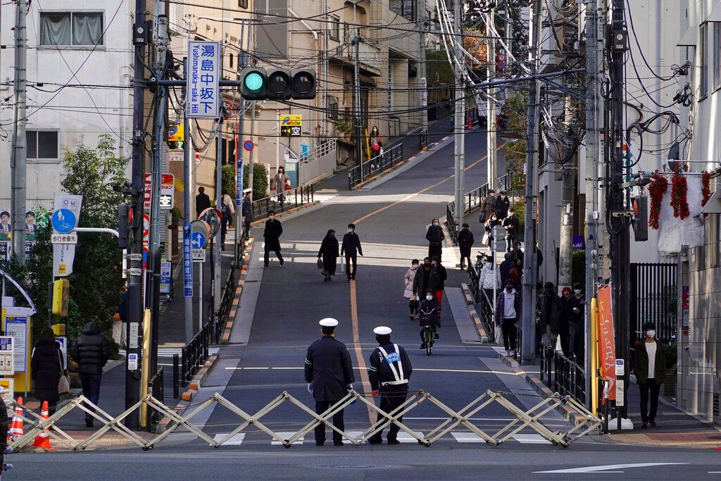 新冠疫情肆虐，日本警察在東京湯島天滿宮的入口管控遊客進入。（美聯社）