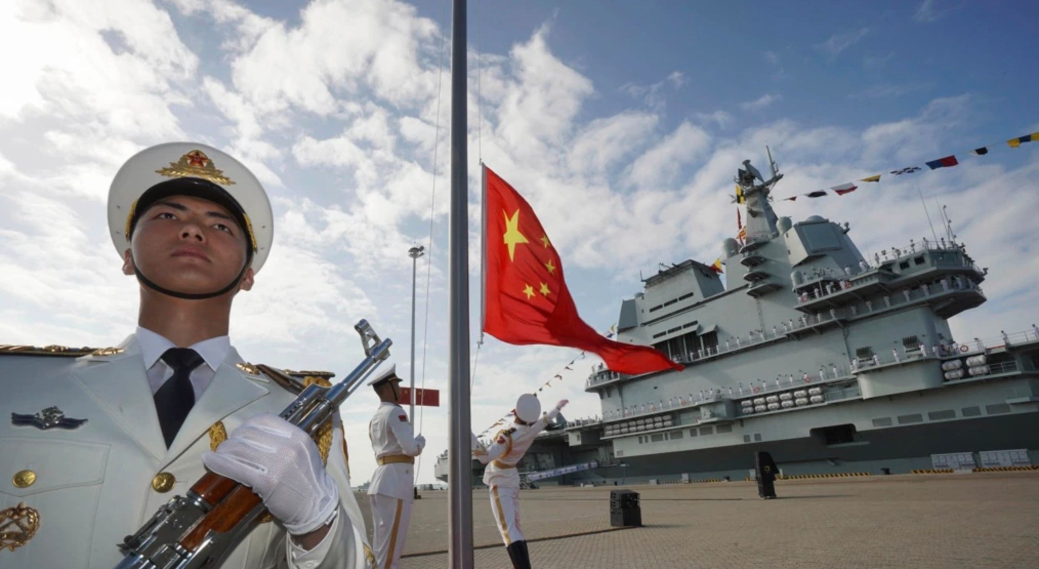 中國航母山東號停泊在海南省的一個海軍基地，解放軍士兵在舉行升旗儀式。（美聯社）