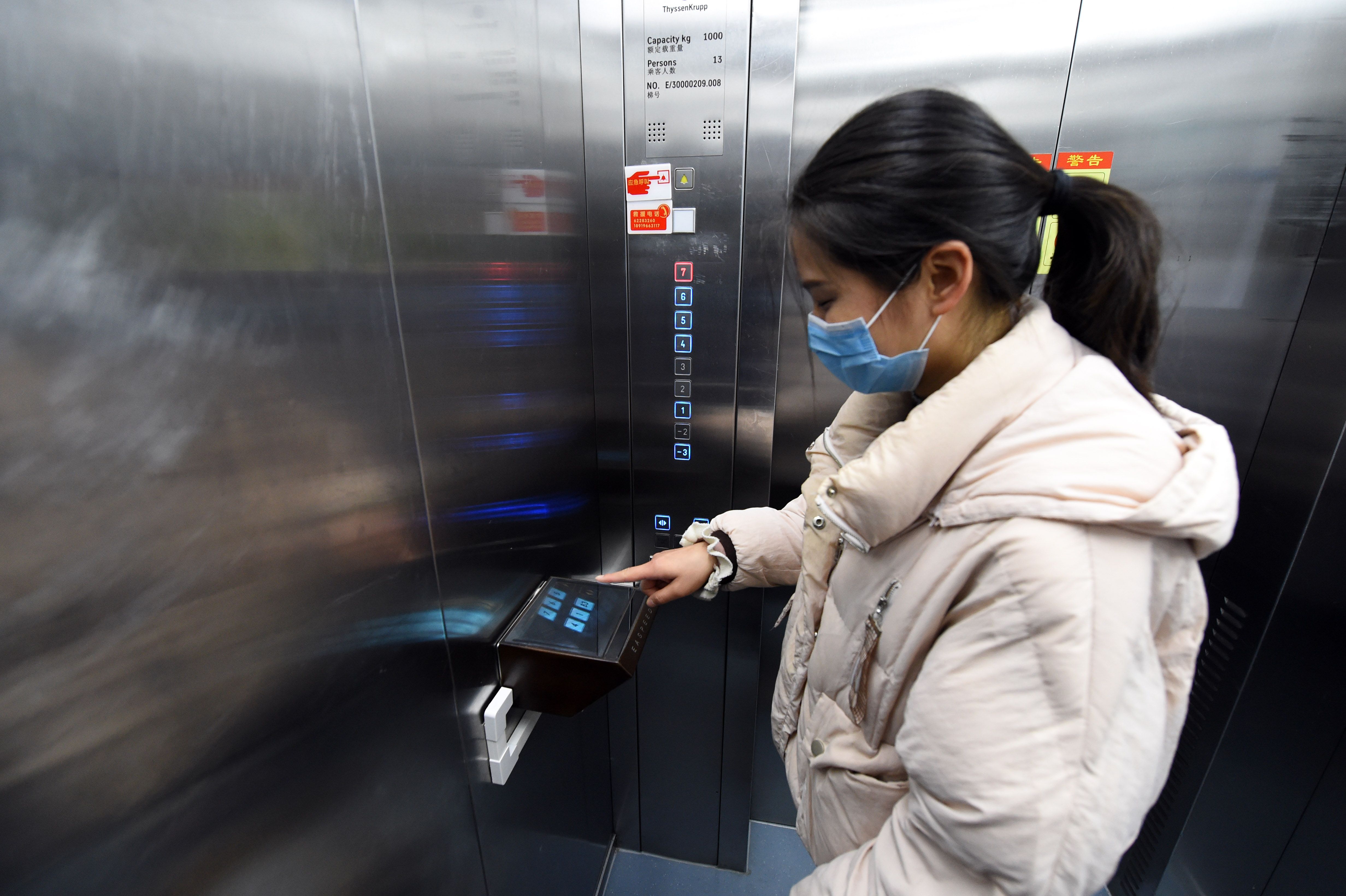 在位於合肥市的中國科學技術大學附屬第一醫院,乘客用“無接觸電梯按鈕”操作電梯。(新華社)