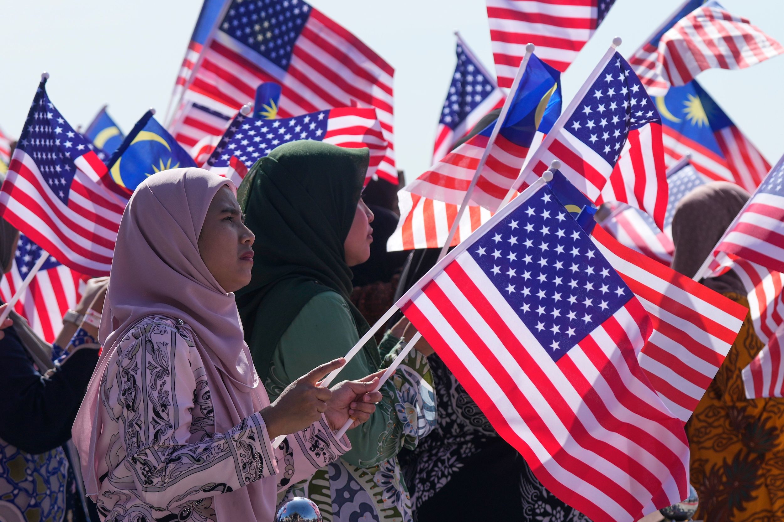 2025年10月26日、アメリカのトランプ大統領がマレーシアのシュバン・クアラルンプール国際空港に到着、マレーシアの市民が両国の旗を手に迎える。(AP通信)