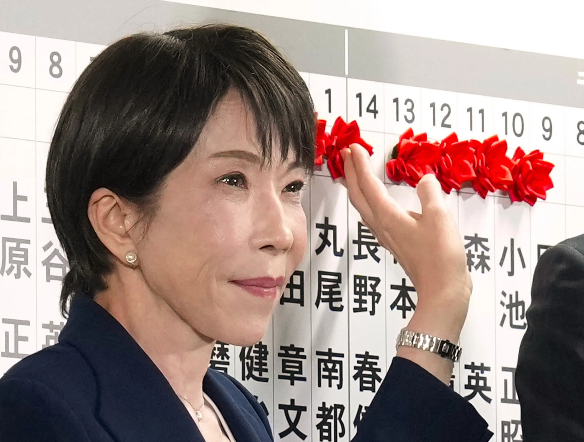 2026年2月8日,日本首相兼自民黨總裁高市早苗在黨總部為勝選者貼花。(美聯社)