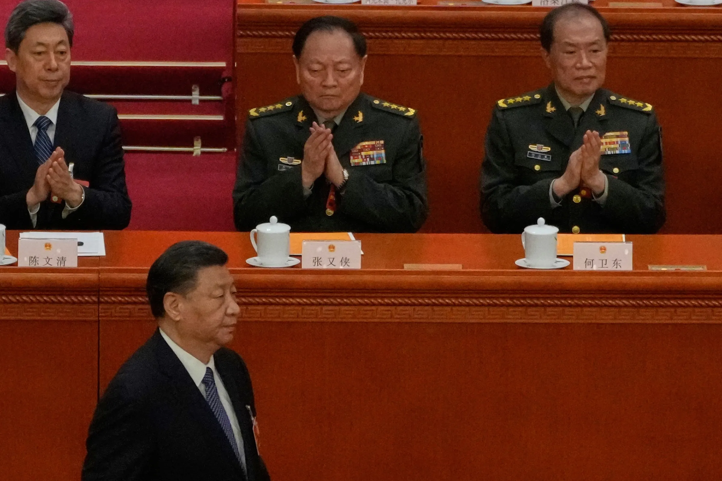 2023年3月12日,中國國家主席習近平在人民大會堂出席全國人民代表大會,走過時任中央軍委副主席張又俠和何衛東的座位前。(美聯社)