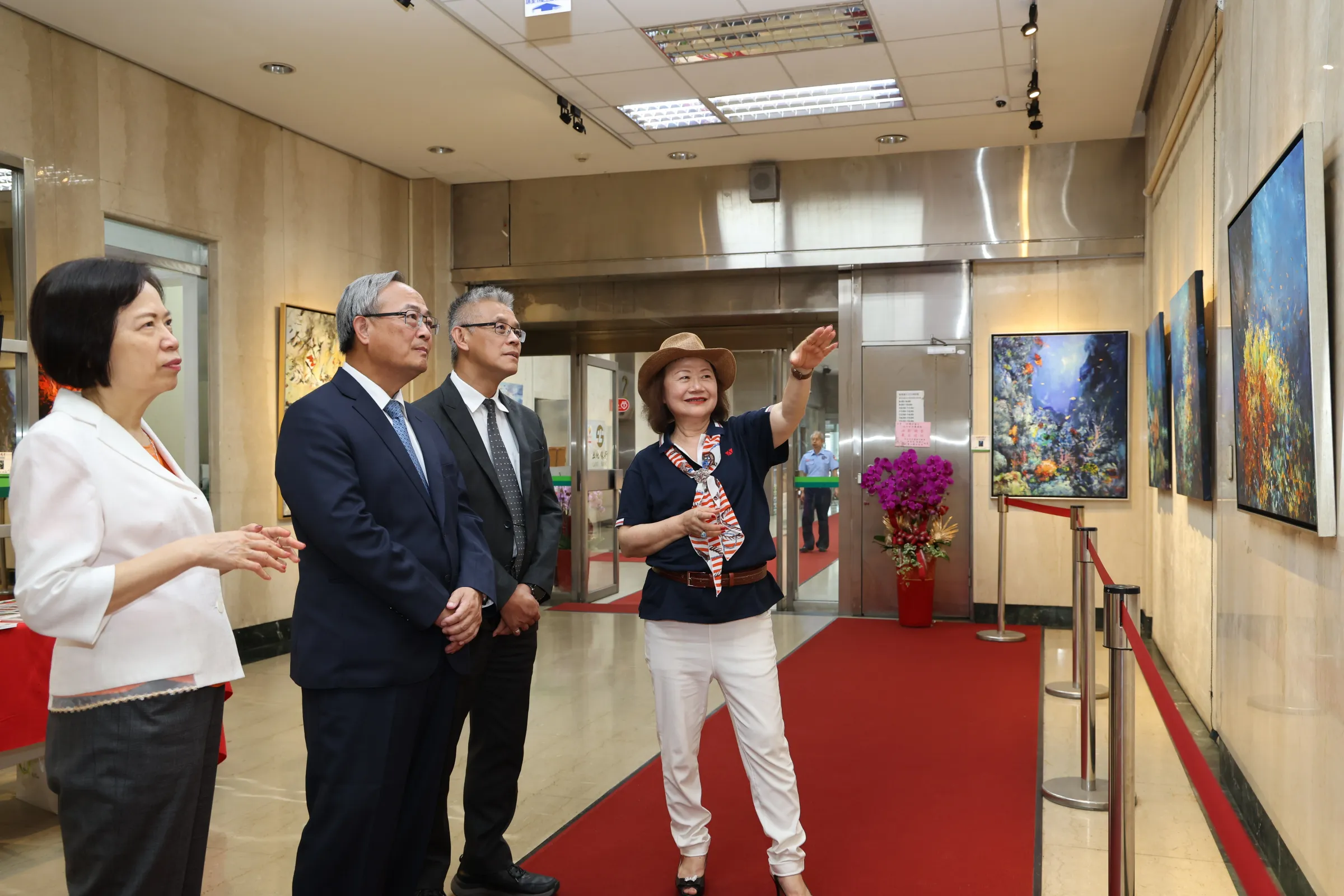 知名藝術家范巧貞(右一)為土地銀行總經理張志堅(左二)、主任秘書鄭瑟琴(左一)、授信審查部經理潘忞作(右二)導覽其畫作。