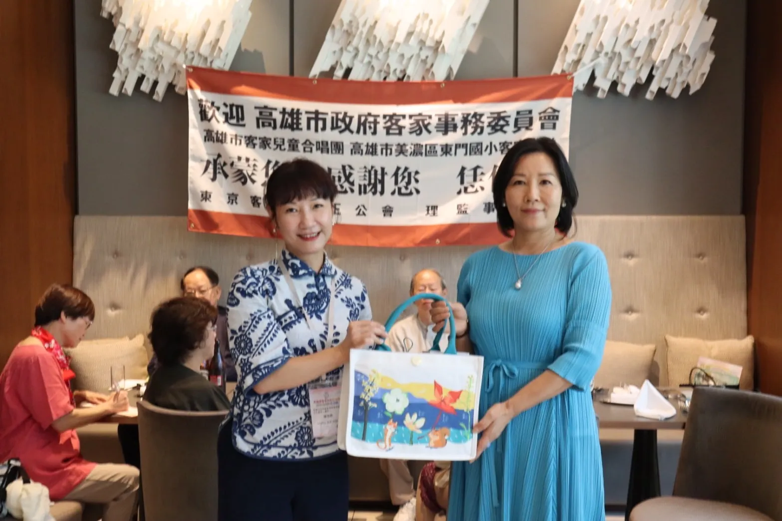高雄客委會主委楊瑞霞(左)贈送紀念品給東京客家崇正公會會長盧杏惠。(圖/高市客委會提供)