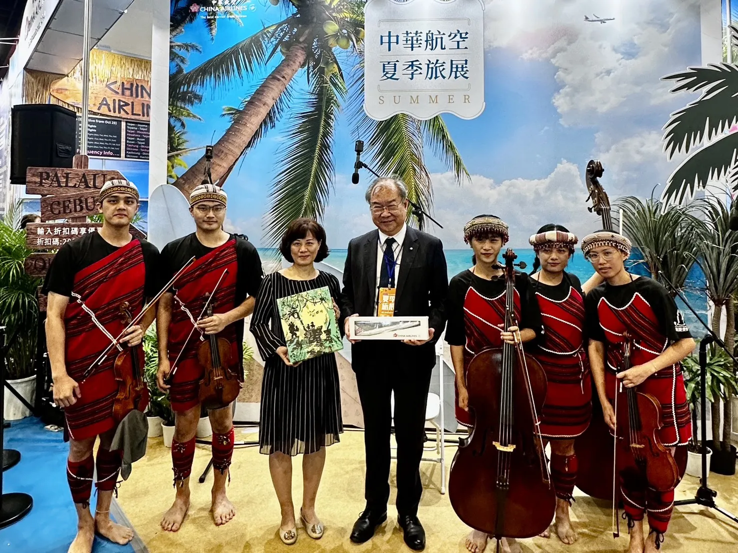 華航夏季旅展以海灘風情打造主題攤位,邀請親愛愛樂弦樂團演出,董事長高星潢(中)親臨現場,為旅展揭開序幕。(華航提供)