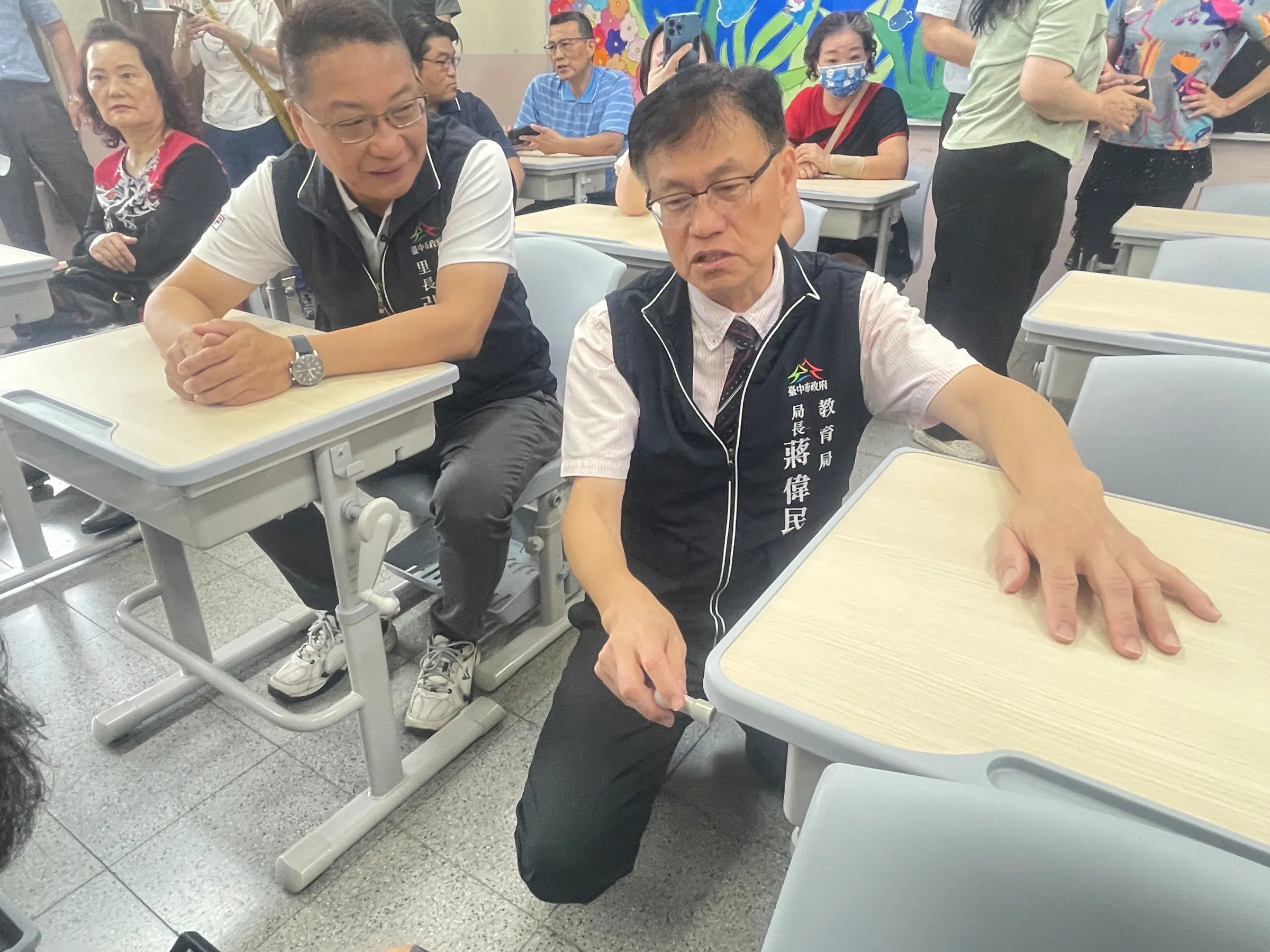 臺中市政府教育局長蔣偉民親自示範調整課桌椅高度。(圖/臺中市政府教育局)