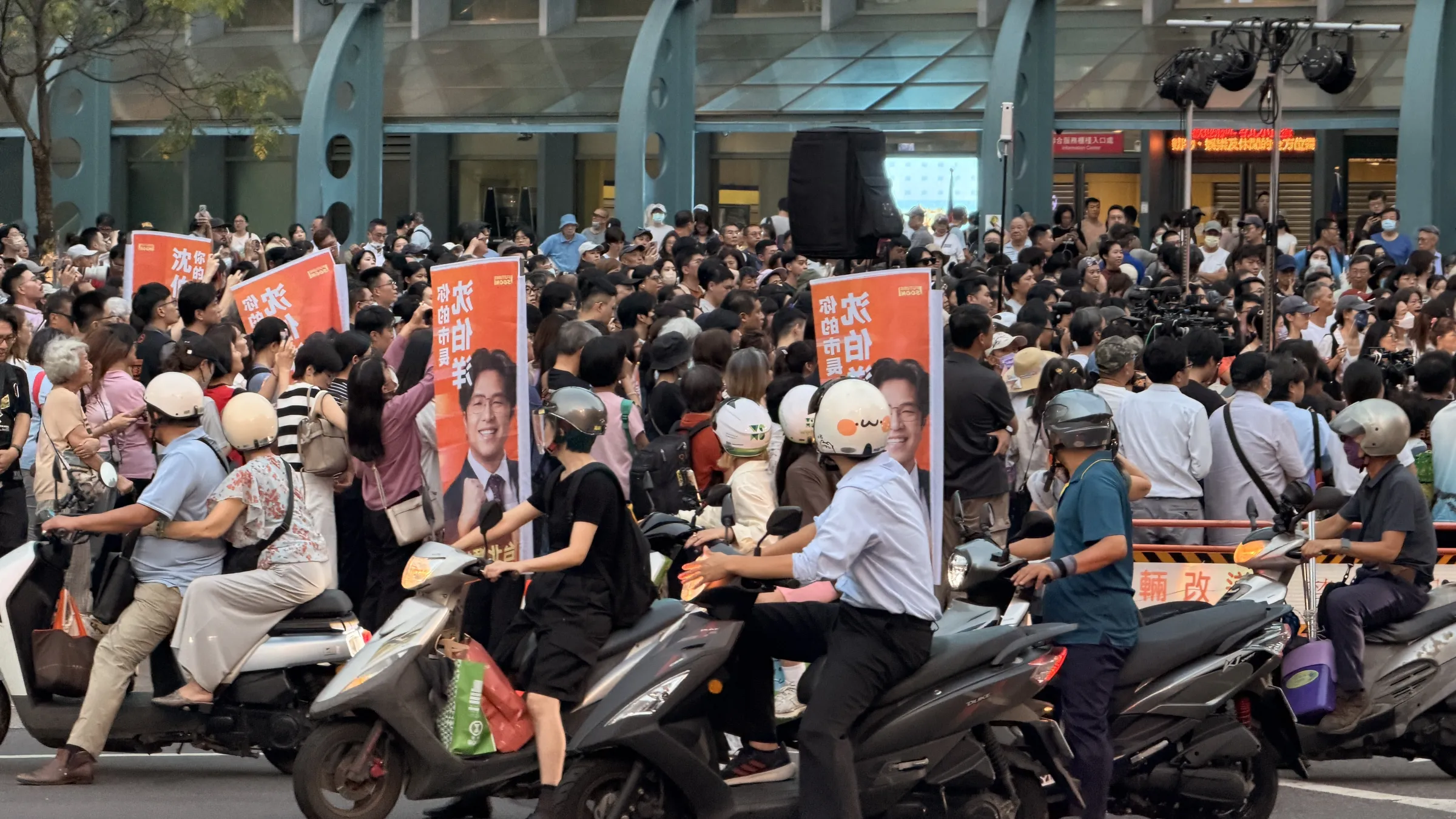 20260930-民進黨台北市長參選人沈伯洋30日傍晚於台北小巨蛋外舉辦「肥皂箱」活動,路過機車騎士停等紅綠燈期間轉頭張望。(鍾秉哲攝)