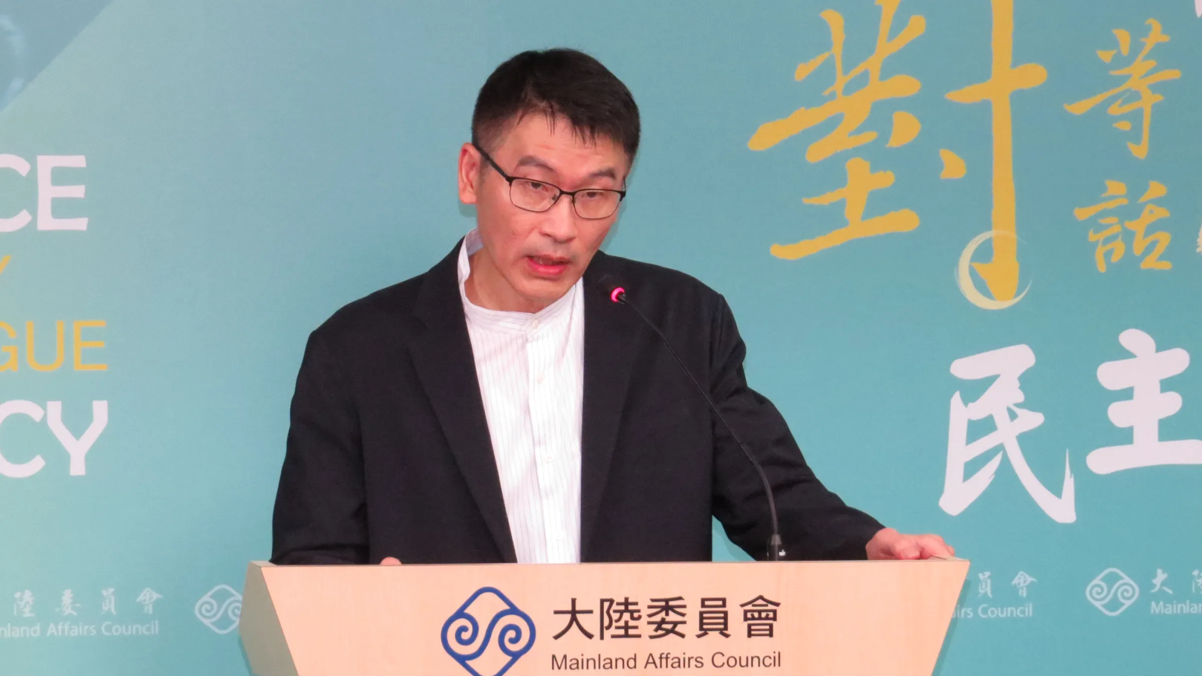梁文傑主持例行記者會,說明政府修法應對「跨境鎮壓」的方向,舉例在美國只要受到外國指示,最高可以判刑10年。(楊騰凱攝)