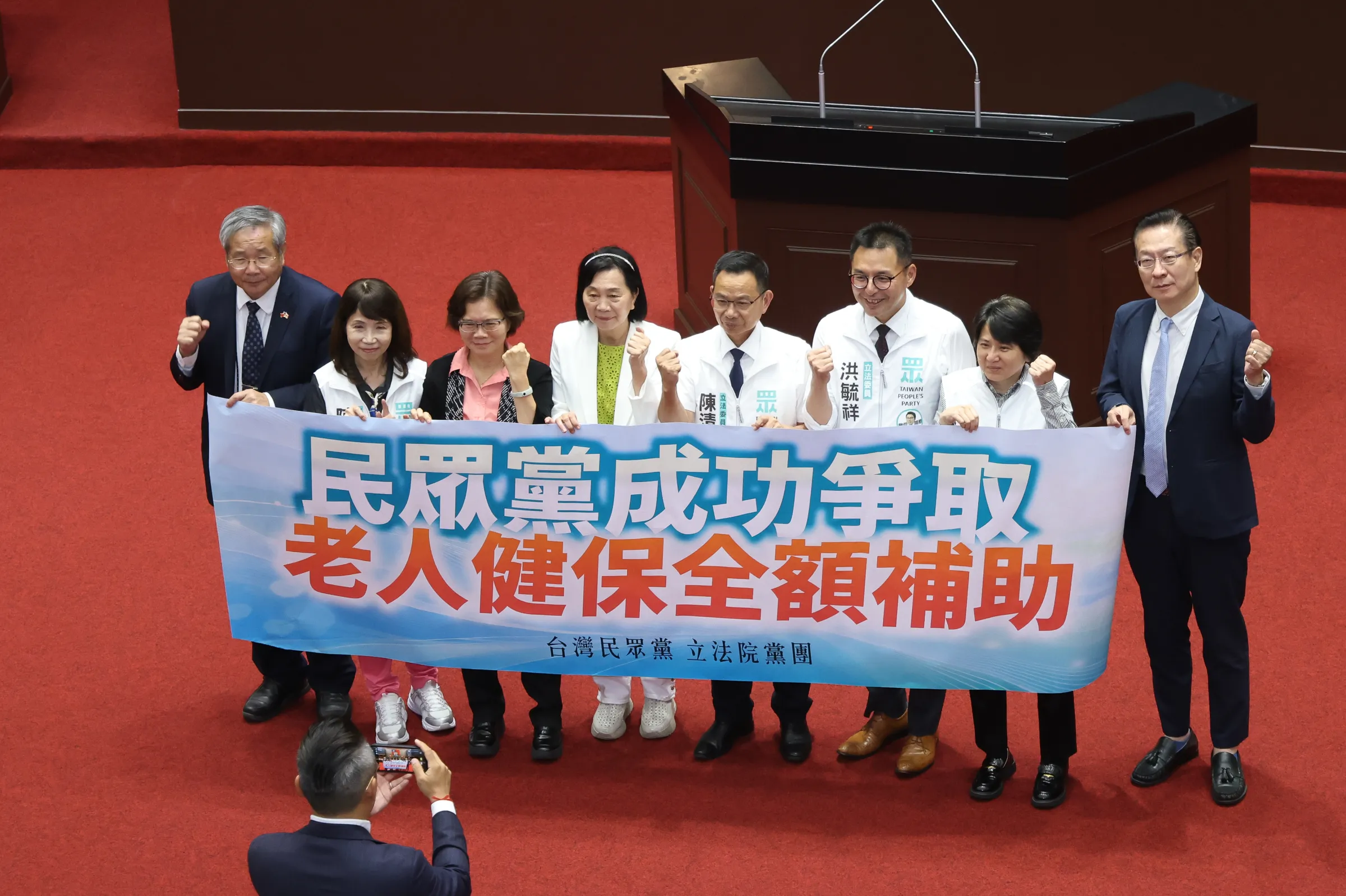 20261016-老人福利法第二十二條修正草案,三讀通過後民眾黨團舉標語合照。(陳品佑攝)
