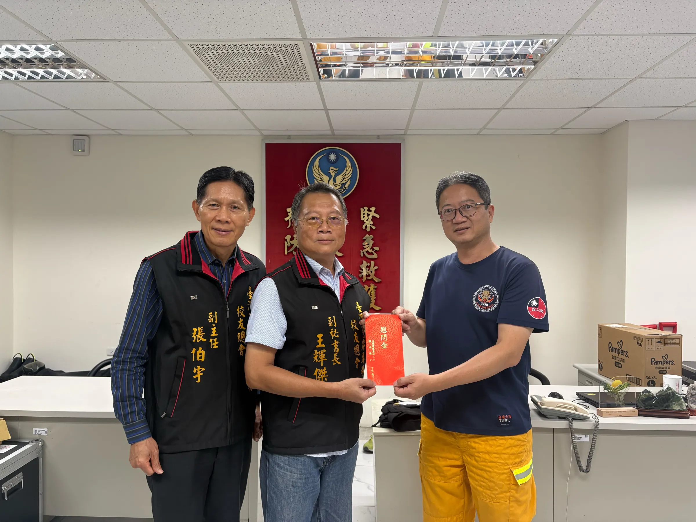 警專校友總會校友服務處副主任張伯宇左、副秘書長王輝傑中,代表總會致送慰問金,由莊青山小隊長右代為接受,協助轉交正在高雄休養的邱楷紘。(圖/警專校友總會提供)