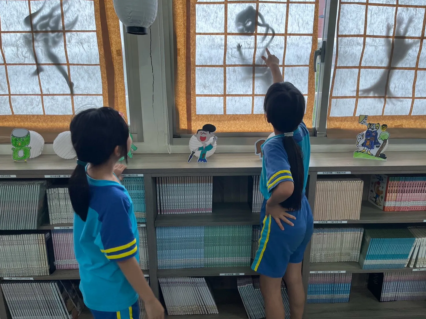 學生觀察窗上的妖怪剪影,探索圖書館內的主題布置。(圖/雨聲國小提供)