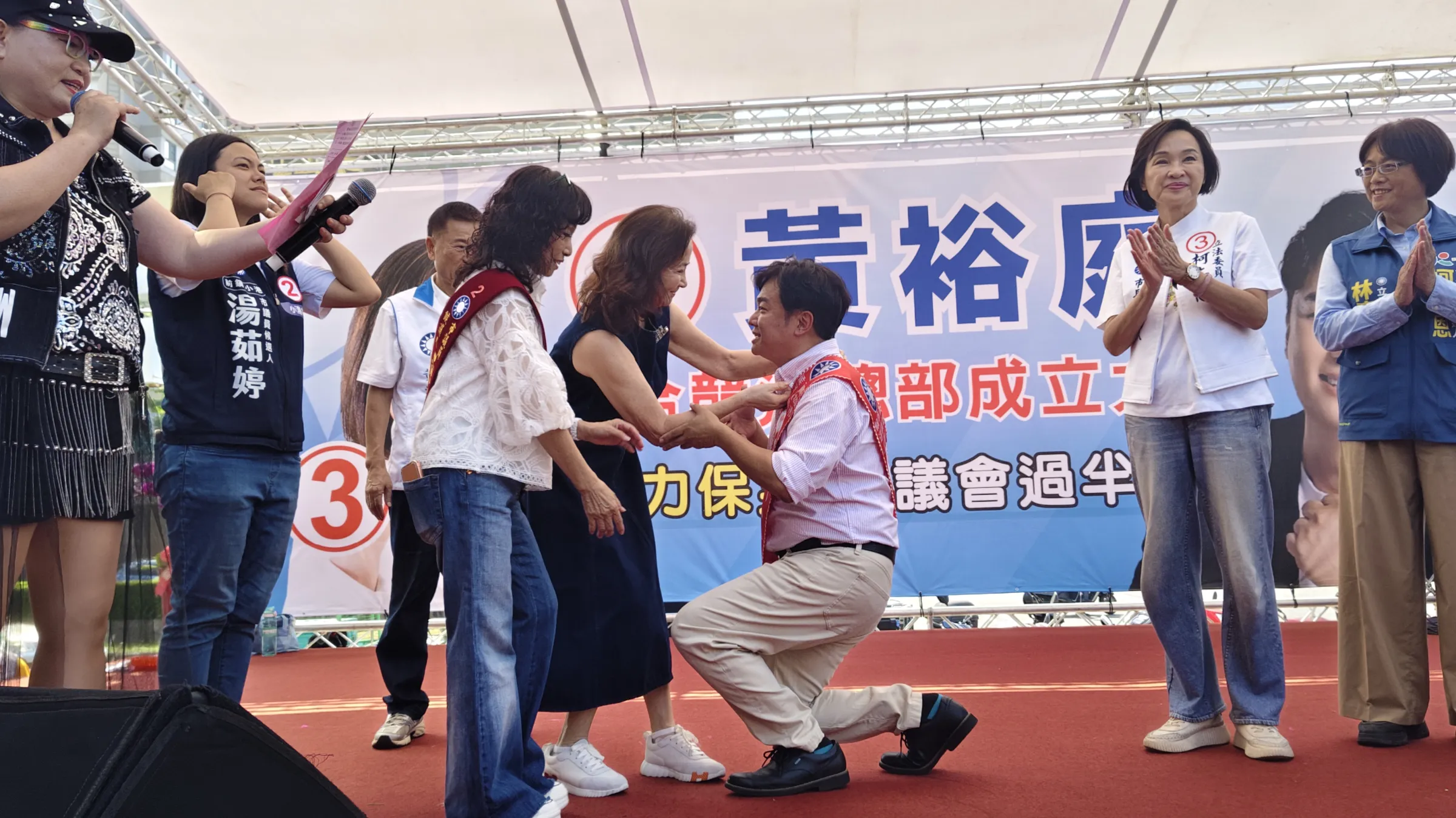 前副總統吳敦義夫人蔡令怡特別由台北南下,為單膝下跪的黃裕庭披上競選彩帶,象徵著責任與熱忱的代代傳承,畫面相當溫馨感人。(圖/徐炳文攝)
